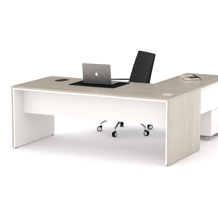 Mesa de despacho operativa en forma de L de ADM Mobiliario escolar Alcantarilla, con acabados en madera clara y blanco, equipada con ordenador portátil y silla ergonómica.